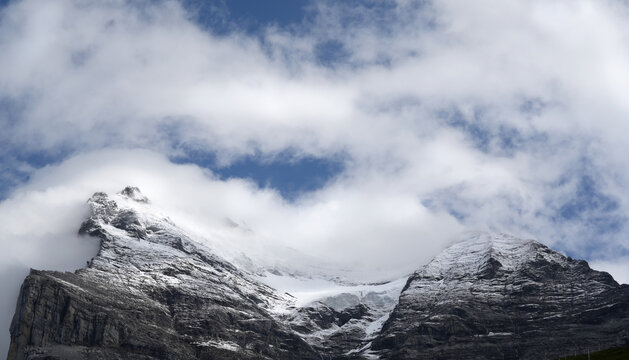 Snow-capped Swiss mountain ridge near Kleine Scheidegg under a cloudy sky, showcasing rugged terrain and glacial features in the Bernese Alps region