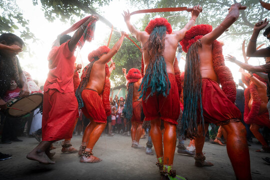 Munshiganj, Bangladesh - 13 April 2025: View of fiery red and orange-clad performers with flowing hair energetically dance, raising swords in a vibrant, rhythmic display.