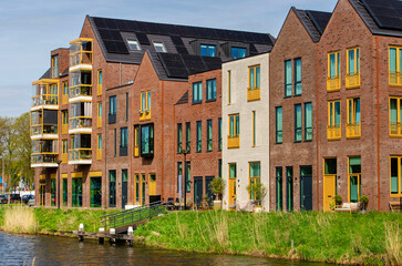Obraz premium Vianen, The Netherlands, April 15, 2026: row of recently built canal houses with brick facades along a canal