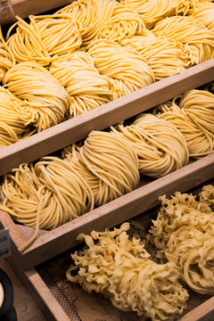 Tiered wooden display trays of fresh spaghetti nests and mafaldine pasta at Eataly Aventura Italian food market