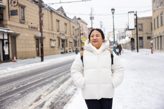 Portrait Beautiful asian fat woman smile happy travel and Standing on Sidewalk with Mountain and Cityscape Background. Enjoying a Sunny Winter Day in a Picturesque Town. posture suggests curiosity
