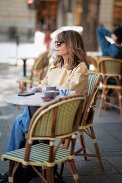 Confident and attractive middle-aged woman sitting in an outdoor cafe in the city