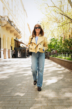 Blond haired middle-aged woman walking throught a city street on a spring day