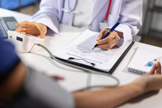 Female doctor is measuring blood pressure of patient and writing medical records on clipboard in hospital or clinic, healthcare and medical concept.