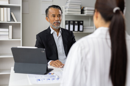 Senior businessman interviewing female job candidate in office.