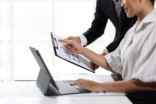 Business people are collaborating on financial analysis, reviewing charts and graphs on a digital tablet and clipboard, business growth and market trends in an office meeting.