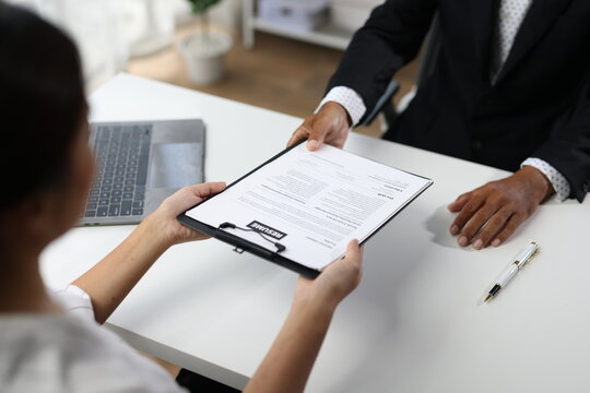 Senior executive receiving a resume or application from a candidate during a professional recruitment process in office meeting, discussing career opportunities and employment.