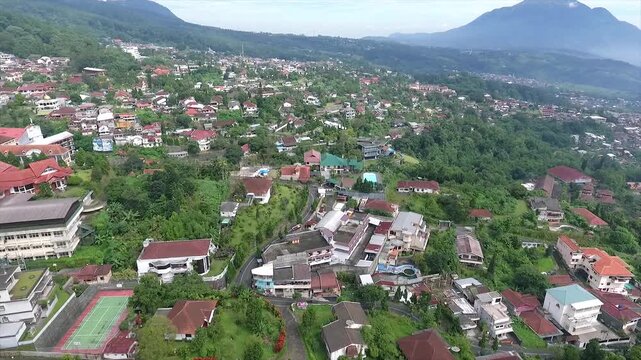 Aerial 4K view of a villa on the hillside of Puncak Tretes and the lush mountain landscape of East Java, Indonesia.