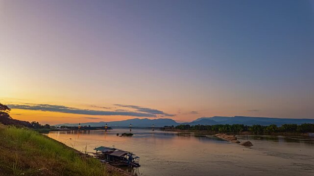 Time lapse Golden twilight illuminates the Fifth Thai&ndash;Lao Friendship Bridge as it spans the Mekong River, highlighting a new landmark of northeastern Thailand at dusk. Dreamy Skies at Sunset