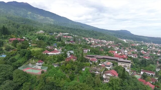 Aerial 4K view of a villa on the hillside of Puncak Tretes and the lush mountain landscape of East Java, Indonesia.
