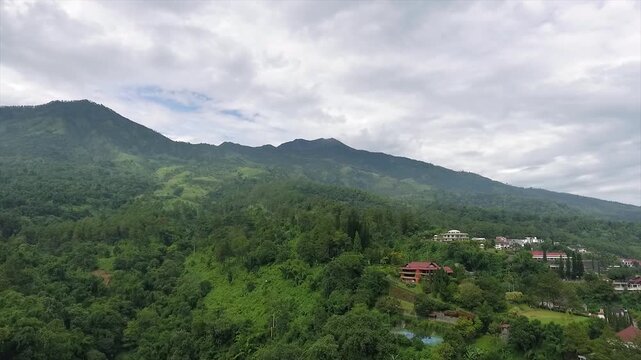 Aerial 4K view of a villa on the hillside of Puncak Tretes and the lush mountain landscape of East Java, Indonesia.