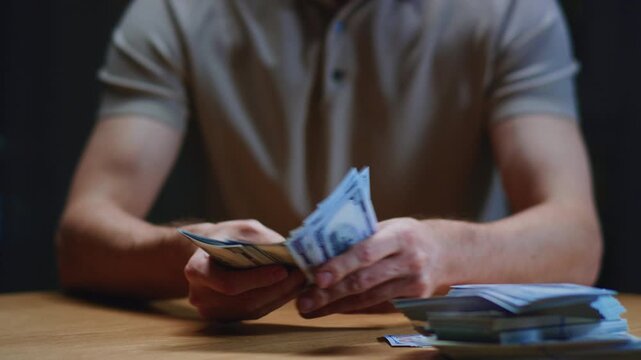 Man investor counting US Dollar bills, close-up. Male trader holds bundle of money, Considers USD at home, evening. Make payment, or have loan. Person manages budget. Hundred paper money cash.