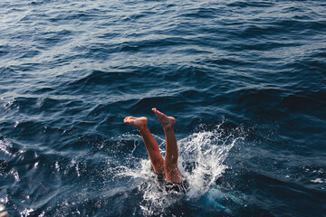 Person diving into deep blue ocean water creating splash © mariamontoyart