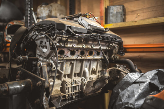 Close-up of a dirty, old car engine block with visible wiring and components in a workshop