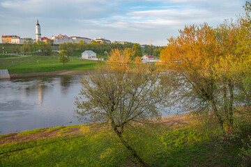 Obraz premium Scenic Cityscape of Mogilev with River and Spring Trees at Sunset with copy space