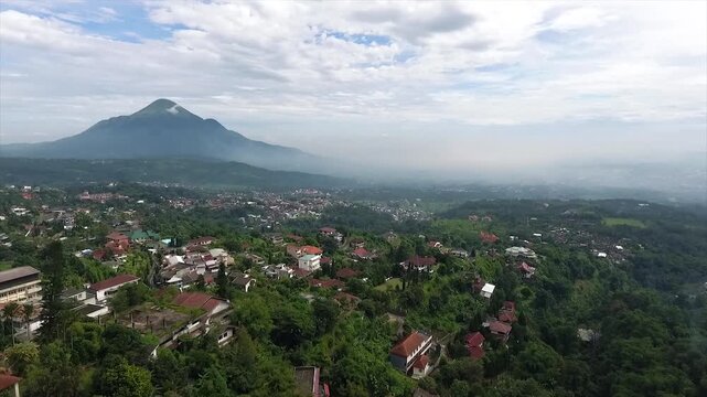Aerial 4K view of a villa on the hillside of Puncak Tretes and the lush mountain landscape of East Java, Indonesia.