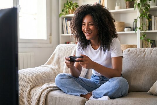 Young woman laughing passionately while enjoying a video game on her couch