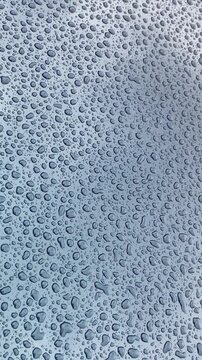 Close-up texture of rain water droplets and condensation on a blue glossy car surface,4K.