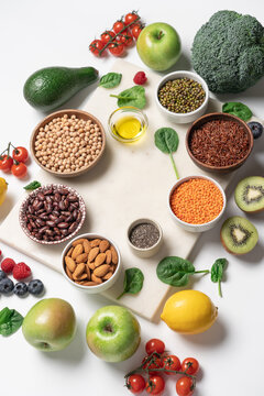Bowls of beans, grains, vegetables, fruits, and berries for healthy protein meal with immune boosting and anti-inflammatory benefits on light marble background with copy space