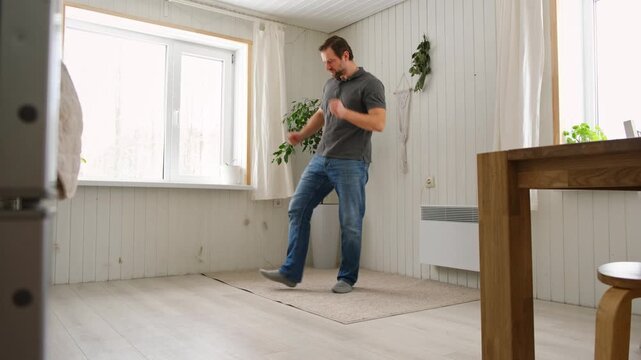 Handsome bearded man dance, have fun at home listens song, moves to music, feels overjoyed, celebrate good news, relish carefree life looks happy. Young adult male twirls, grooves, dancing in kitchen