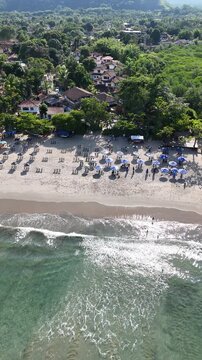 Vista panor&acirc;mica a&eacute;rea da Barra do Sahy destacando mar tranquilo, vegeta&ccedil;&atilde;o e estrutura de praia com turistas, cen&aacute;rio t&iacute;pico de ver&atilde;o no litoral brasileiro