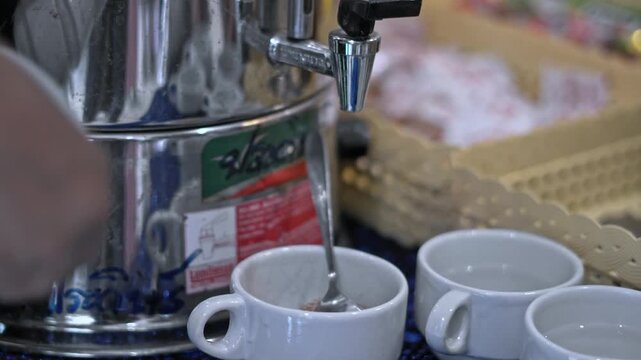 A close-up view of a hand pouring tea from a stylish teapot into small cups. The scene showcases an elegant tea setup, highlighting the artistry of tea service and the serene atmosphere associated wit