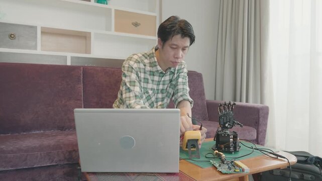 A focused individual works on a robotics project, utilizing a laptop and various tools in a contemporary workspace. The environment reflects creativity and technical skill, showcasing the fusion of te