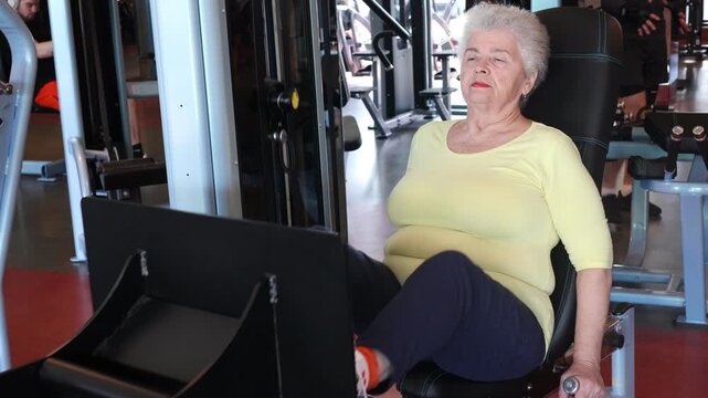 Senior woman exercising on a leg press machine in gym. sarcopenia prevention.  Active aging, strength training, mobility improvement, healthy lifestyle and independence in older age concept.