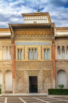Main facade of Mudejar Palace in Royal Alcazar of Seville Spain. Ancient ornate stone carving under cloudy overcast sky