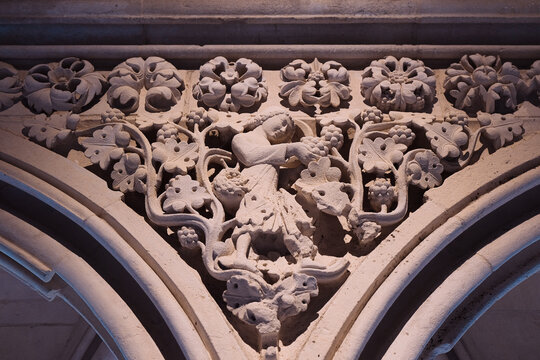 Mont Saint-Michel, France: Detailed stone relief carving of a figure harvesting grapes in the gothic abbey. Medieval sculptural art.