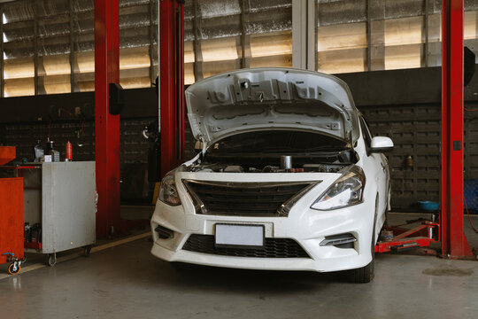 Car maintenance service with open hood in auto repair garage workshop vehicle inspection and engine check concept