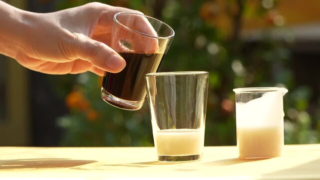 Pouring coffee into condensed milk, making traditional Vietnamese iced coffee in morning light.