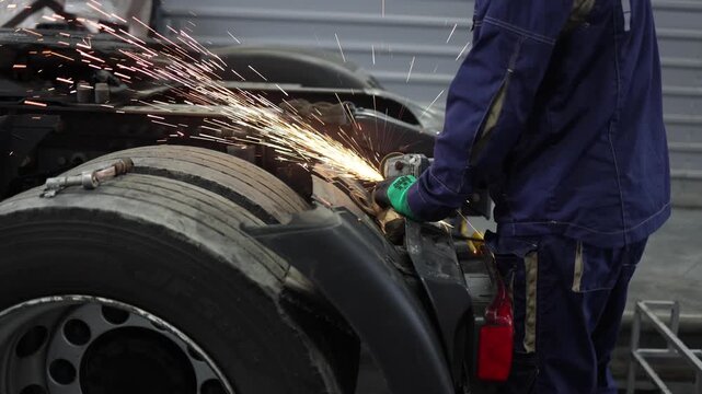 A skilled service worker expertly repairs trucks in a well-equipped workshop, using a grinding machine to meticulously work on vehicle components. The scene showcases dedication and craftsmanship.