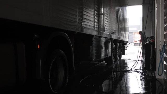 .Inside a spacious car wash, a focused cleaner meticulously cleans the interior of a shiny white truck cabin, ensuring every detail sparkles. Bright lighting highlights the professional atmosphere.