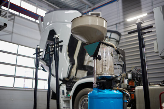 An informative image depicting an oil change machine in a car service area, with a truck boasting a white cab in the background, highlighting professional auto repair services.