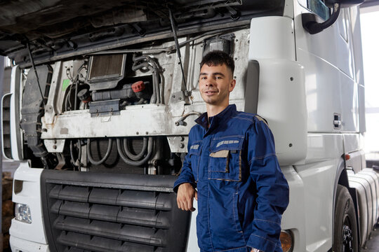 A dedicated service employee stands confidently in front of a white-cab truck, showcasing their professionalism and readiness to tackle any task. This image captures the essence of service with pride.