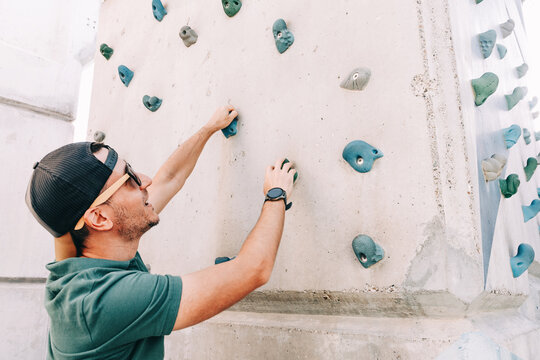 Man bouldering on an artificial outdoor rock climbing wall, focused training for fitness, strength and determination in an active lifestyle