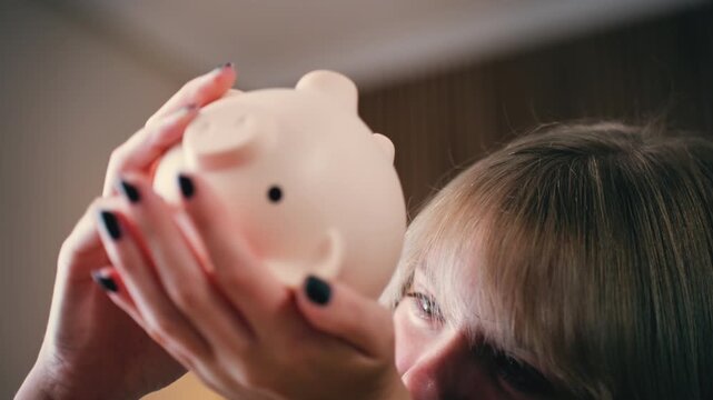 Determined teenage girl with blonde hair meticulously putting shiny coin into piggy bank, Concept  importance of saving money, personal finance, and economic planning from young age