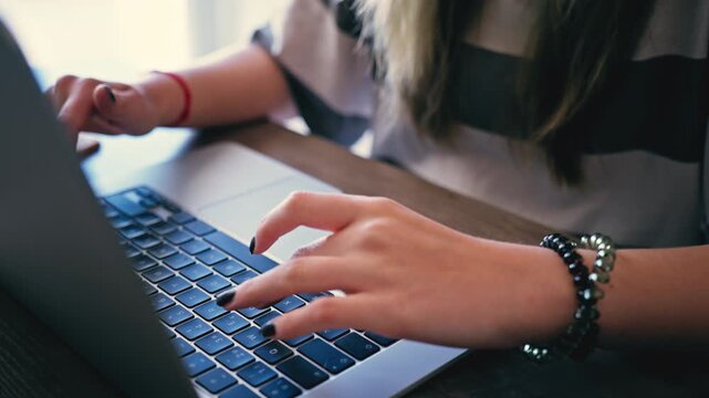 Close-up of an unrecognizable woman's hands typing on laptop keyboard at desk,  Concept remote work, digital communication, online business in modern office or home setting