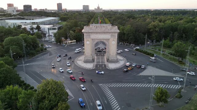 Bucharest, Romania - July 13, 2025. Aerial drone view of the Arch of Triumph monument and the nearby National Rugby Stadium. Cityscape featuring the historic landmark and sports arena.