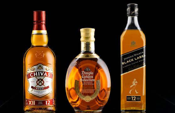Studio shot of blended Scotch whisky bottles including Chivas Regal 12, Dimple Golden Selection and Johnnie Walker Black Label isolated on black background.