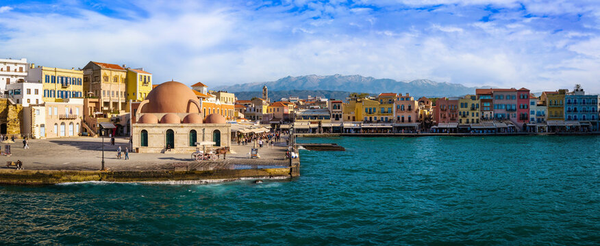 Breathtaking Chania Old Port. Aerial 16K panorama. Pink Giali Tzamisi mosque with colorful Venetian houses and horse carriages on waterfront. Crete Greece travel scenery. World Print 20000px summer