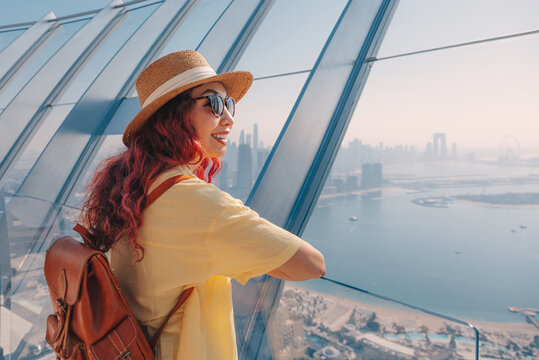 Young woman tourist on a viewpoint admiring Palm Jumeirah and Dubai skyline, embracing travel and adventure
