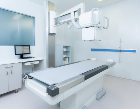 Bright, empty hospital radiology room featuring a modern digital X-ray machine and examination table, captured with wide-angle perspective and clean clinical lighting