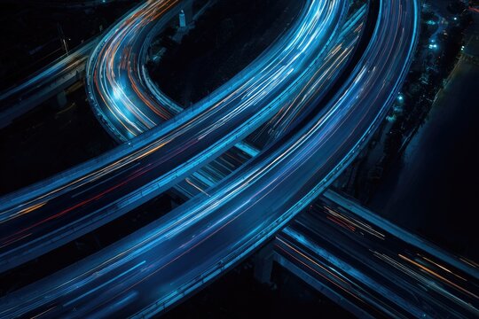 A mesmerizing long-exposure photograph captures the vibrant flow of traffic on a complex highway interchange at night, creating streaks of blue and red light.