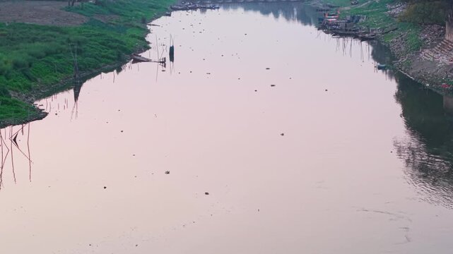 Environmental crisis: A highly endangered Gangetic dolphin struggling to survive and feed in the heavily polluted waters of the River Ganga. 4K aerial establishing shot of the Triveni Ghat confluence.