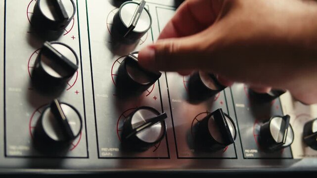 Music studio close up, Close up hands shot of sound engineer using mixing console, remote control for adjusting sound, audio mixer. Musician creates music, makes remix for DJ set. Sound recording