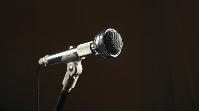 Retro microphone on studio or stage, macro of check sound, hand touch microphone. 