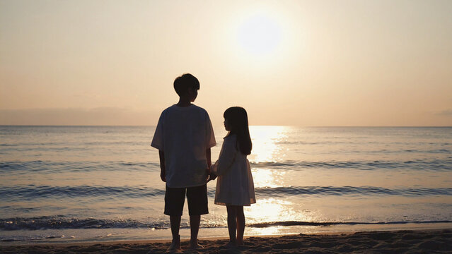 An inseparable brother and sister stand on the seashore against the backdrop of a fabulous vanilla sunset
