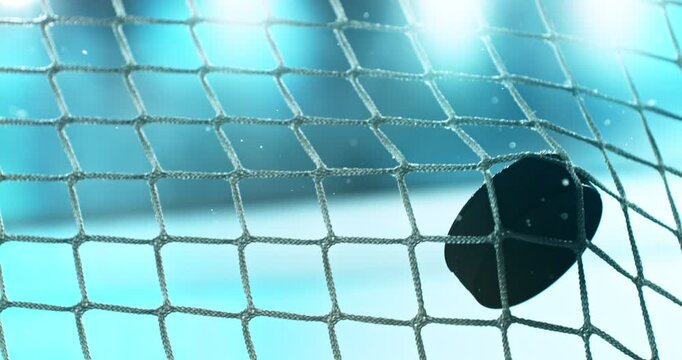 Extreme super slow motion close-up of an ice hockey puck striking the goal net at 1000 fps, with ice particles exploding on impact and a blurred winter stadium and rink in the background.